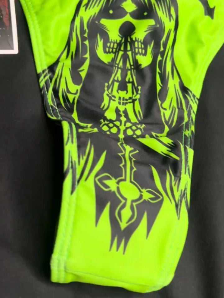 Detalle de un bottom verde neón con una parca y una cruz estampadas en negro